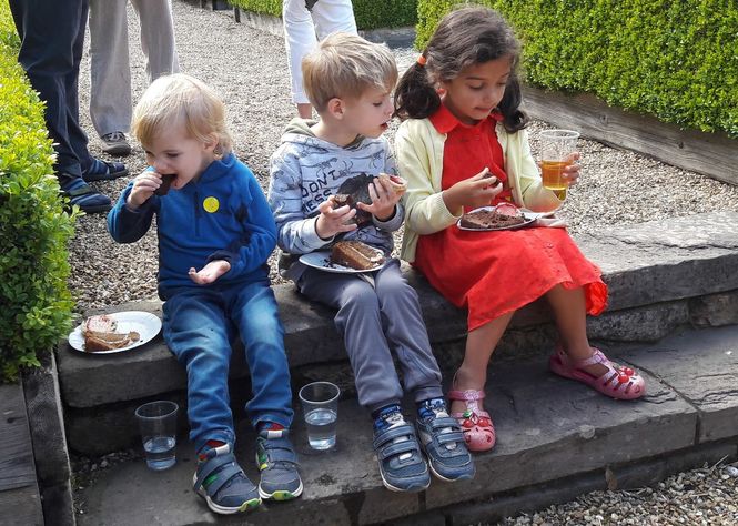 Mmm cake, three younger garden visitors enjoy chocolate cake after an afternoon of garden exploration